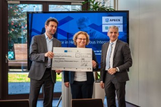 State Secretary Dr. Patrick Rapp passes the Fraunhofer IAF Institute Management the cheque for the APECS funding.